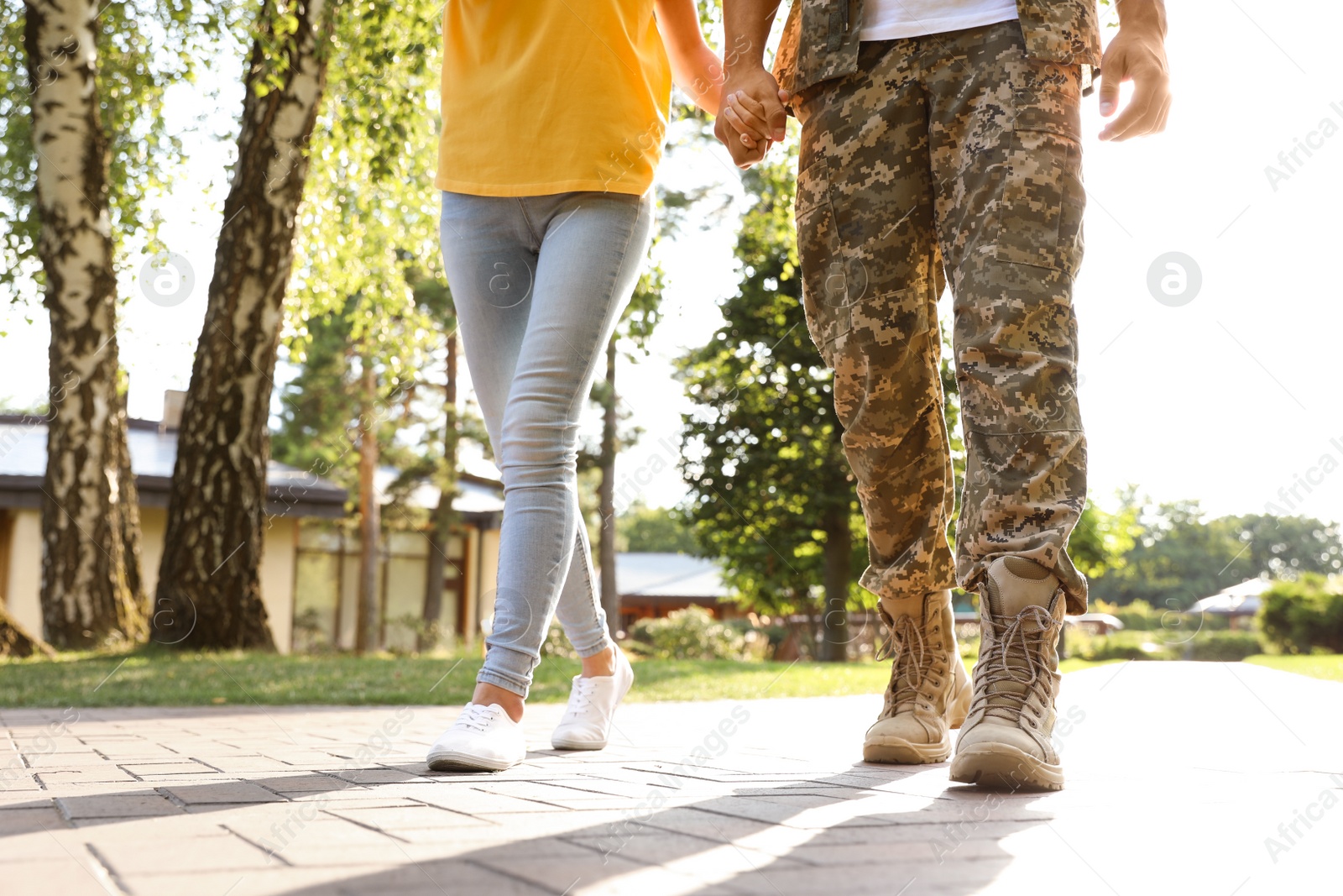 Photo of Man in military uniform walking with his girlfriend at sunny park, closeup