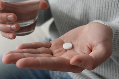 Man with glass of water and pill, closeup