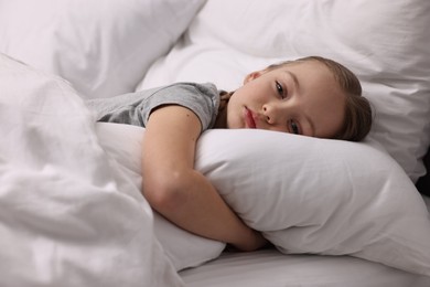 Photo of Little girl suffering from headache in bed