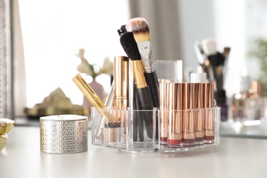 Photo of Luxury makeup products and accessories on dressing table with mirror, closeup