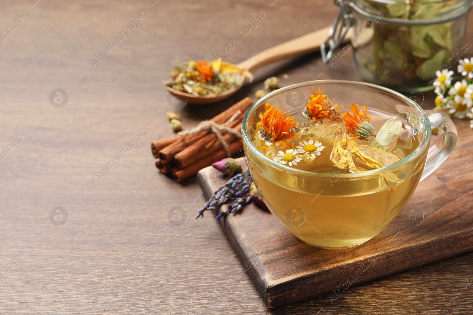 Photo of Freshly brewed tea and dried herbs on wooden table. Space for text