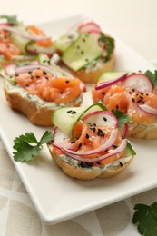 Tasty canapes with salmon served on table, closeup