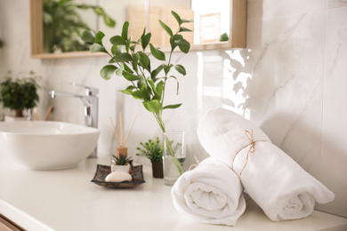 Towels and green plants on white countertop in bathroom. Interior design