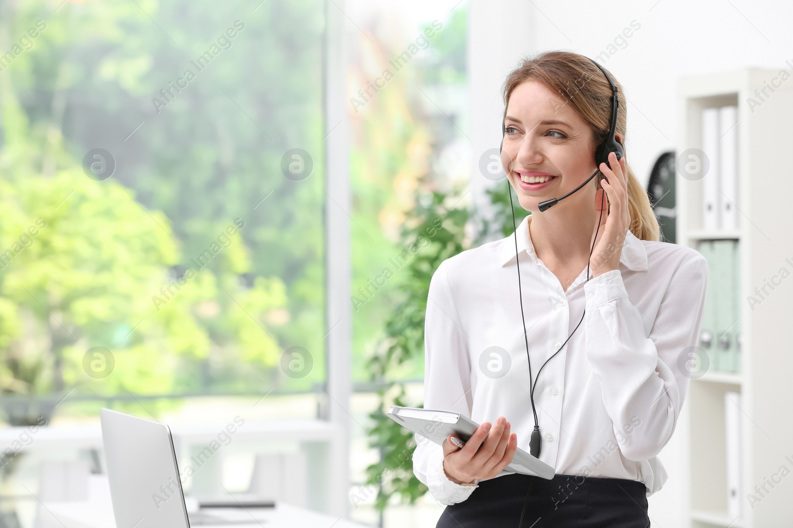 Photo of Young female receptionist with headset in office