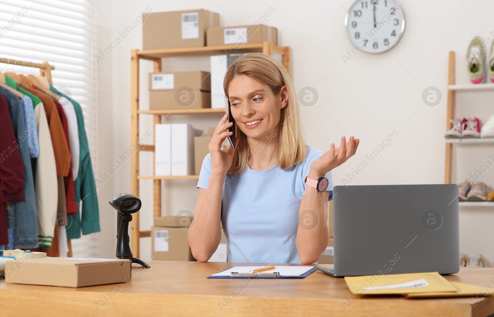 Photo of Seller talking on phone while working in office. Online store