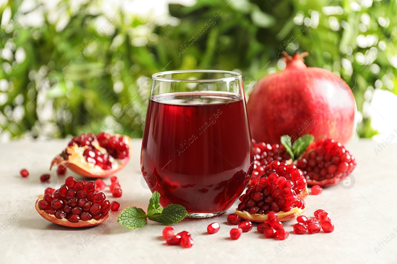 Photo of Composition with glass of fresh pomegranate juice on table