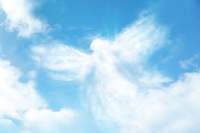 Image of Silhouette of angel made of clouds in blue sky 