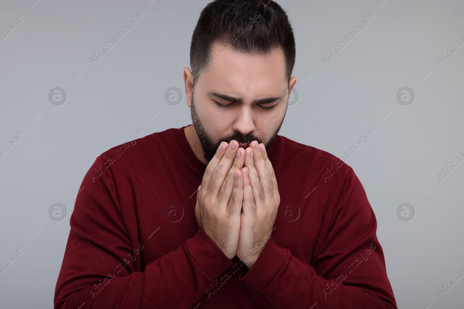 Photo of Sick man coughing on gray background. Cold symptoms