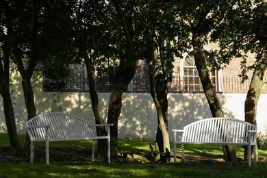 Photo of White wooden benches in park on sunny day