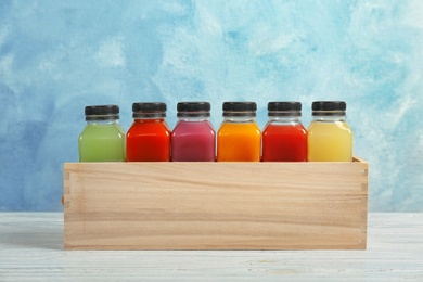 Photo of Wooden crate with tasty juices on table