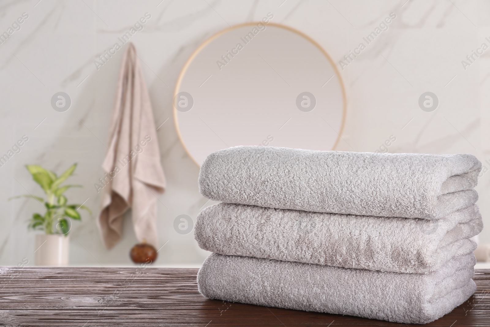 Image of Stack of fresh towels on wooden table in bathroom. Space for text