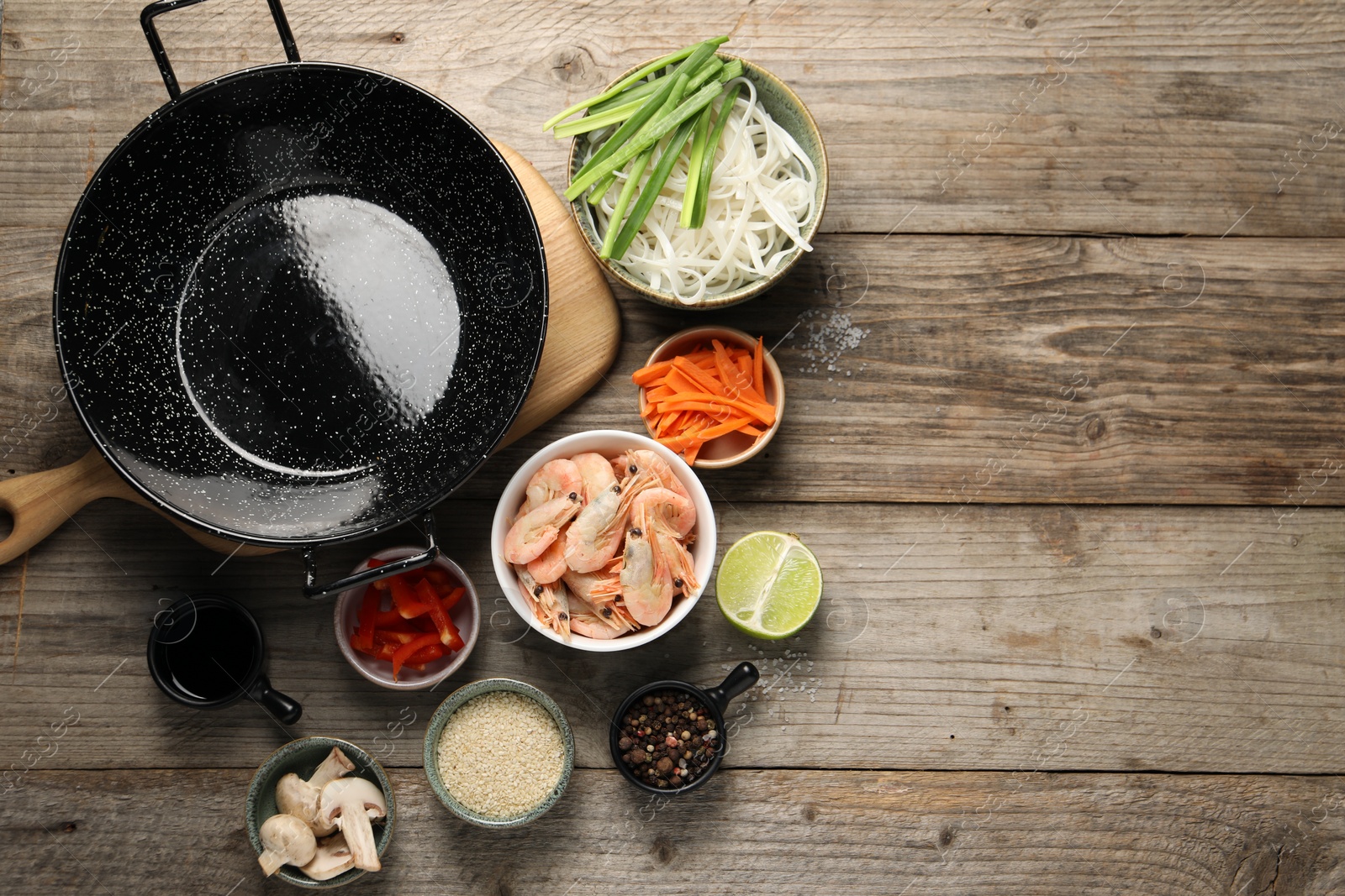 Photo of Flat lay composition with black wok, spices and products on wooden table. Space for text