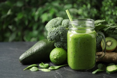 Delicious green juice and fresh ingredients on black table. Space for text