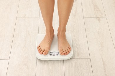 Woman standing on floor scales indoors, closeup