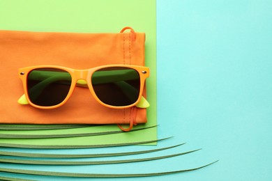 Photo of Stylish sunglasses with bag on color background, top view. Space for text