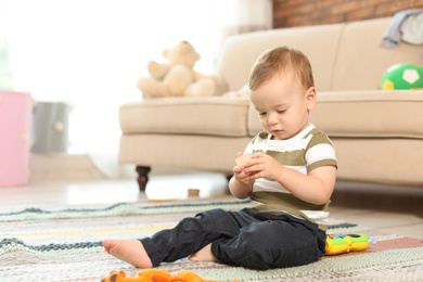 Adorable little baby sitting on floor at home