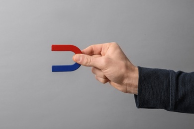 Photo of Man holding magnet on grey background, closeup