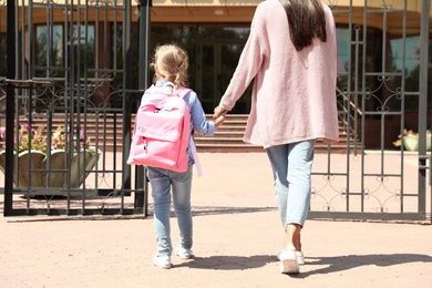 Photo of Young mother taking her little child to school outdoors