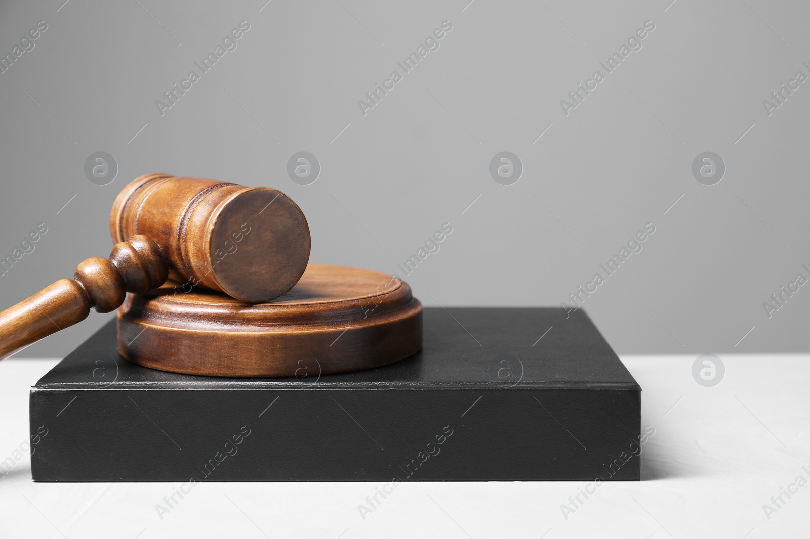 Photo of Law. Book, gavel and sound block on light table against gray background, space for text