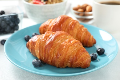 Photo of Delicious breakfast with croissants and berries on white table, closeup