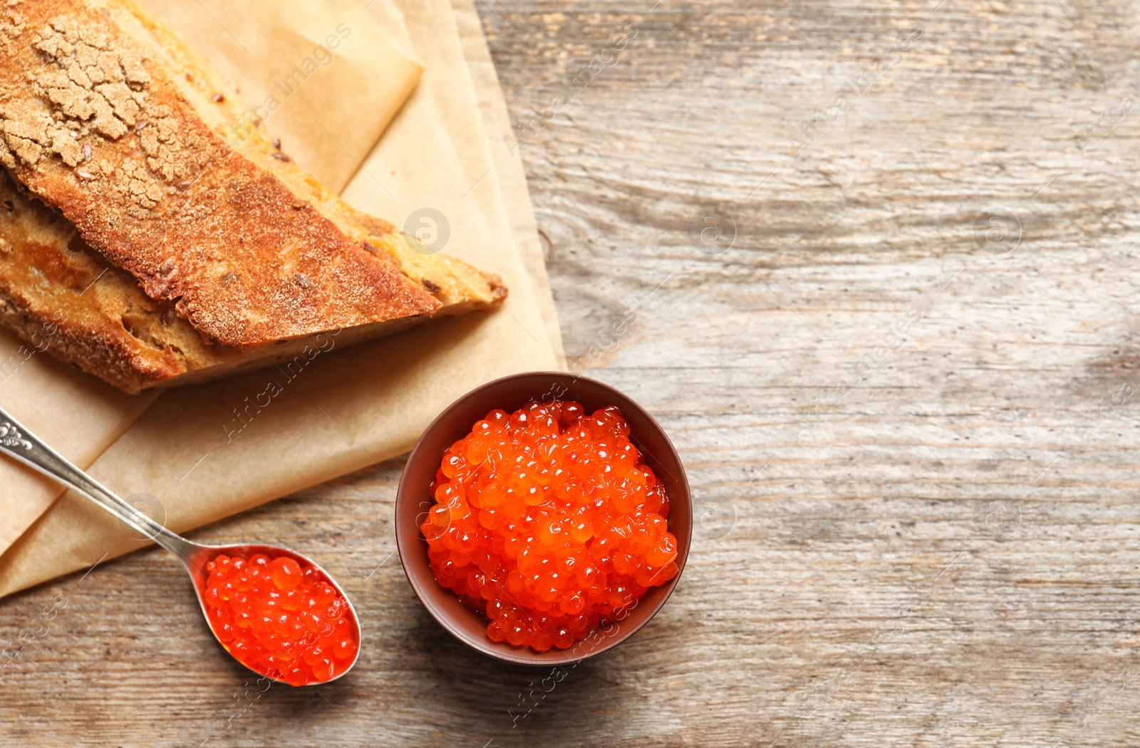 Photo of Bowl and spoon with delicious red caviar on table