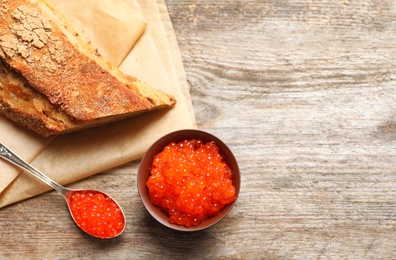 Bowl and spoon with delicious red caviar on table