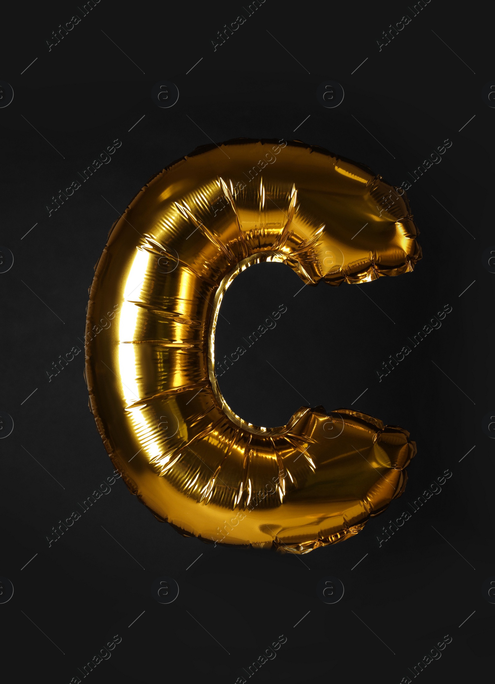 Photo of Golden letter C balloon on black background
