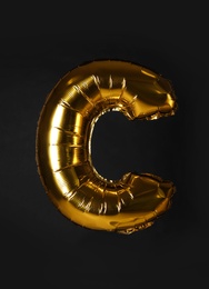 Golden letter C balloon on black background