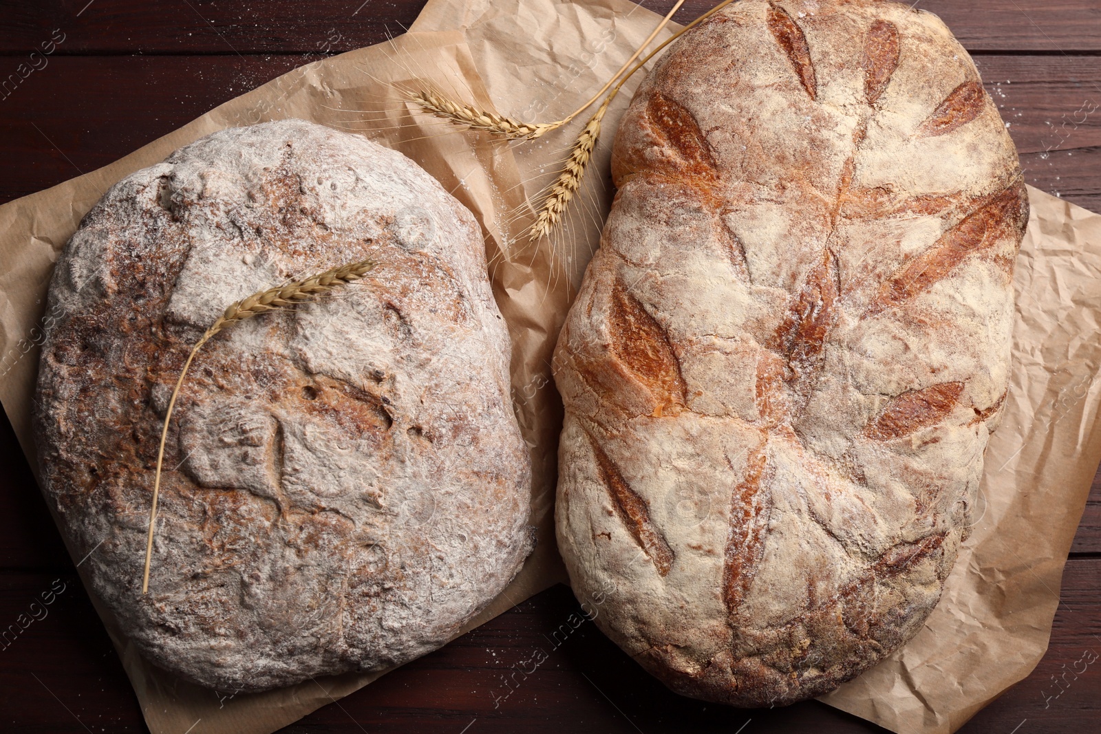 Photo of Tasty freshly baked bread on wooden table, top view