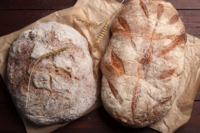 Photo of Tasty freshly baked bread on wooden table, top view