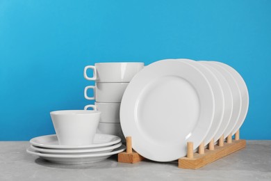 Set of clean tableware on grey table against light blue background