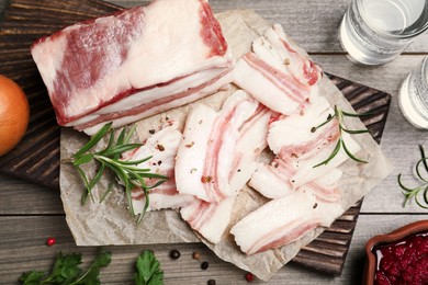 Photo of Tasty salt pork with rosemary and spices on wooden table, flat lay