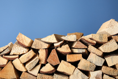 Photo of Cut firewood on blue background. Heating in winter
