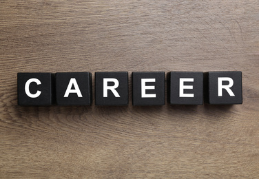 Black cubes with word CAREER on wooden background, flat lay