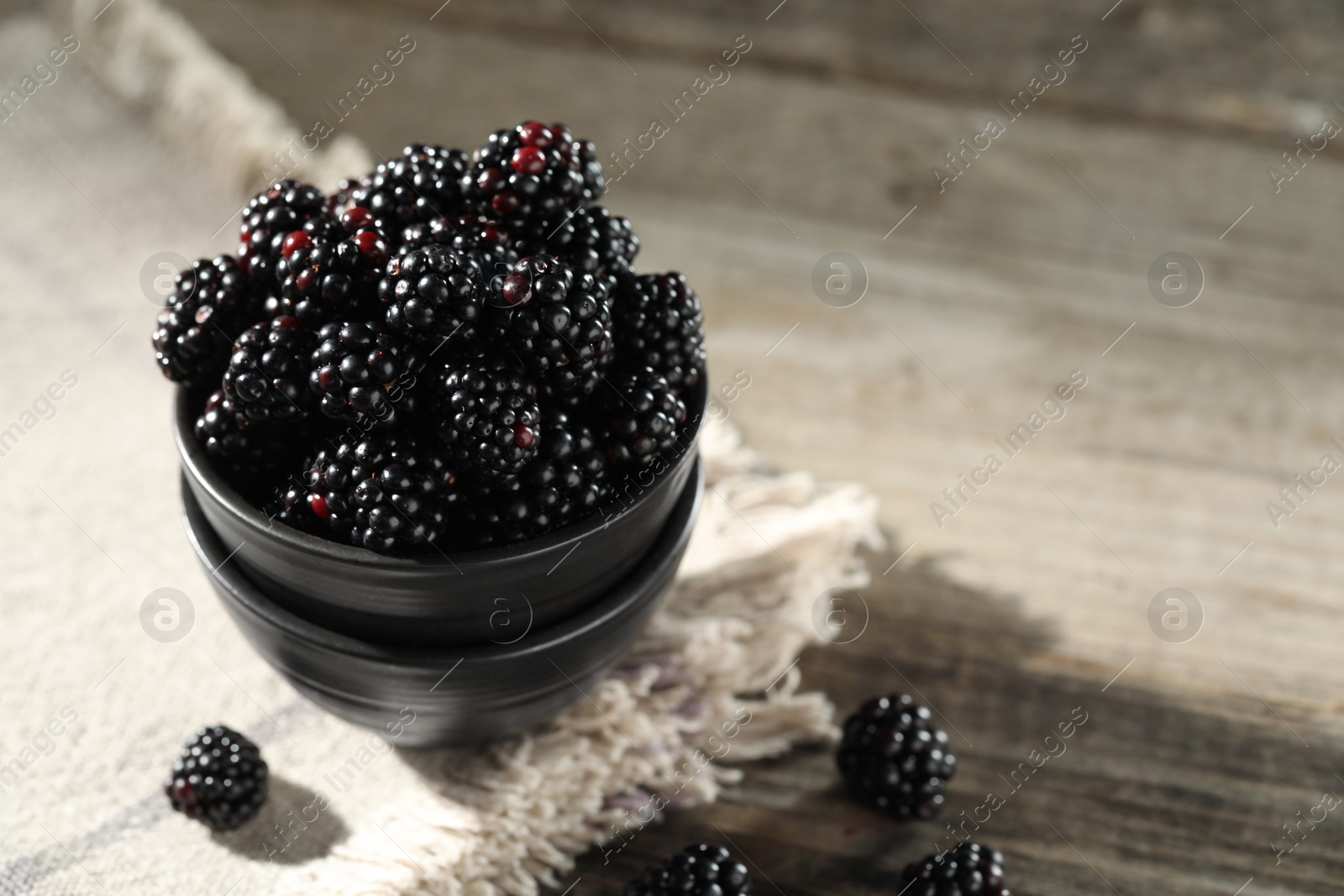 Photo of Fresh ripe blackberries on rustic wooden table, closeup. Space for text