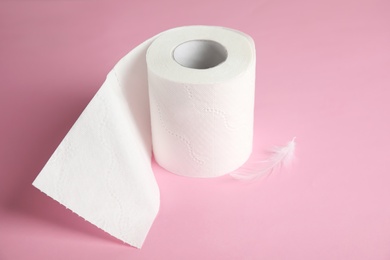 Photo of Toilet paper roll with feather on color background