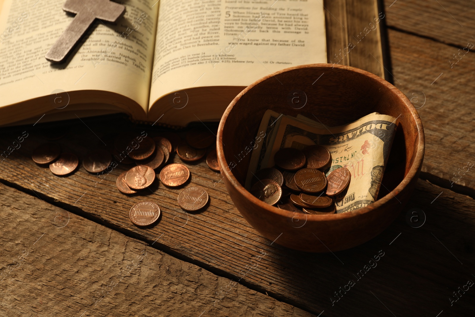 Photo of Donate and give concept. Bowl with coins, dollar banknotes, cross and Bible on wooden table, closeup