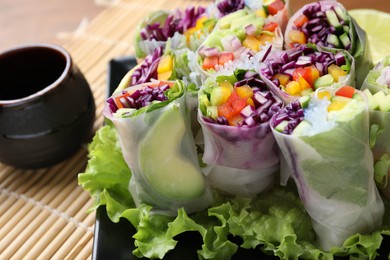 Delicious spring rolls and soy sauce on table, closeup