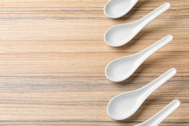 Photo of Miso soup spoons on wooden table, flat lay. Space for text