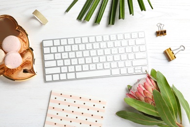 Photo of Creative flat lay composition with tropical flower, macaroons and computer keyboard on wooden background