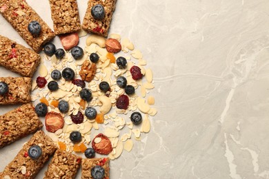 Photo of Tasty granola bars and ingredients on beige marble table, flat lay. Space for text