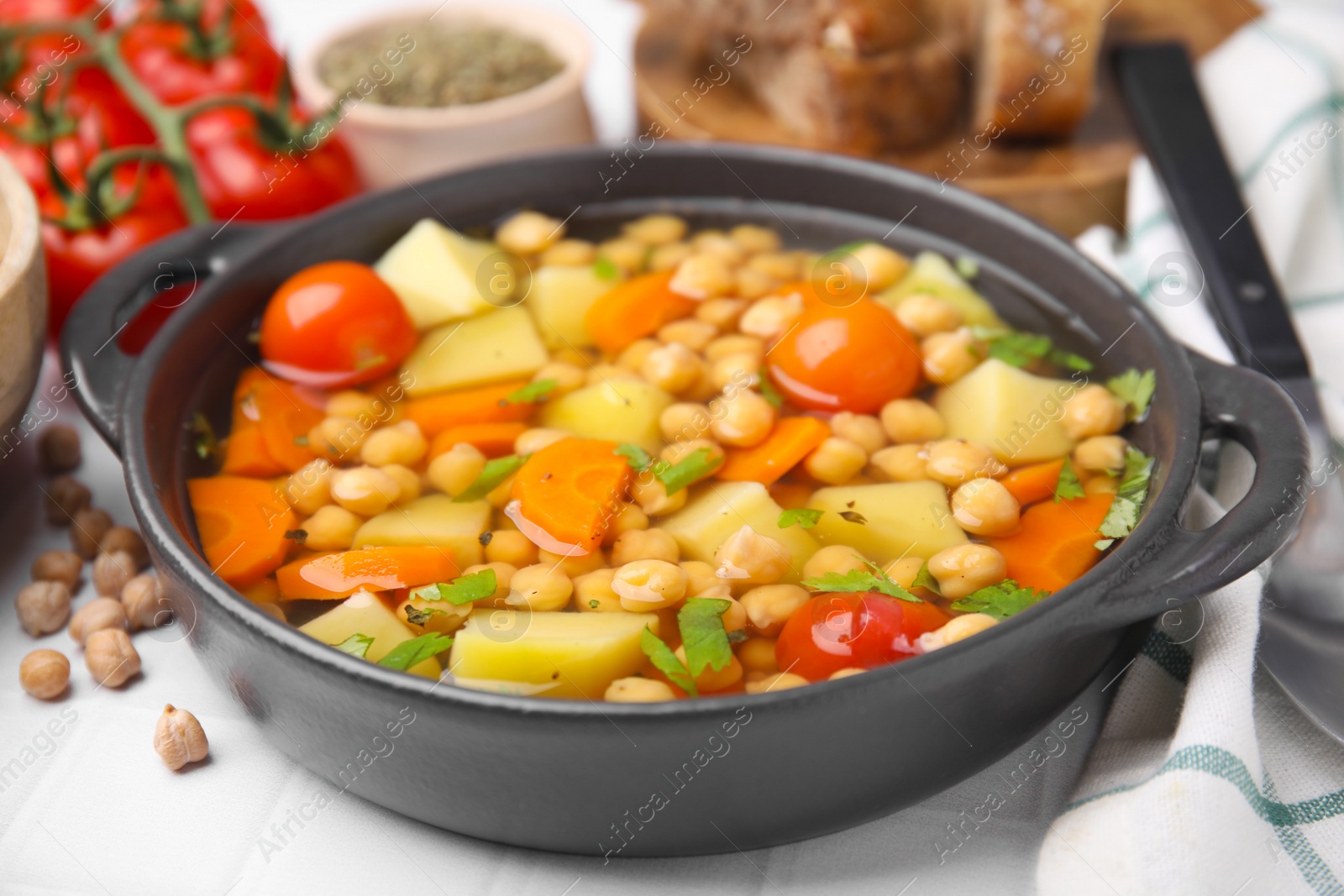 Photo of Tasty chickpea soup served on white tiled table, closeup