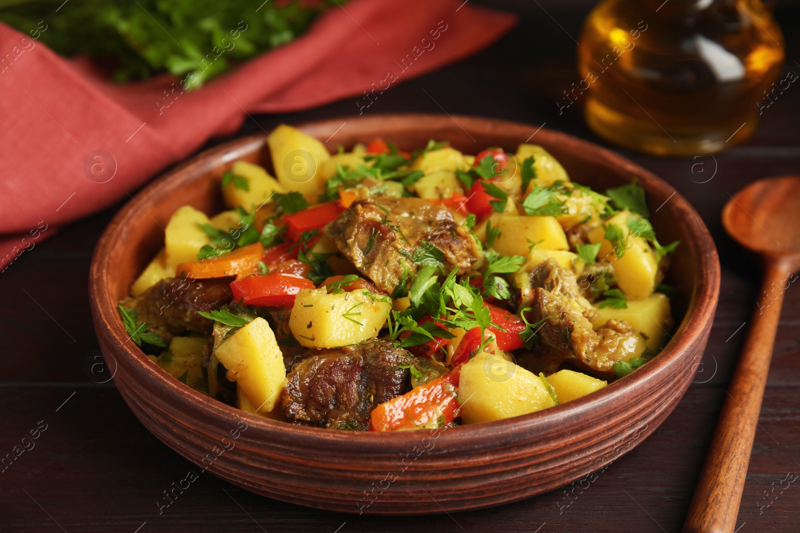 Photo of Tasty cooked dish with potatoes in earthenware served on wooden table, closeup