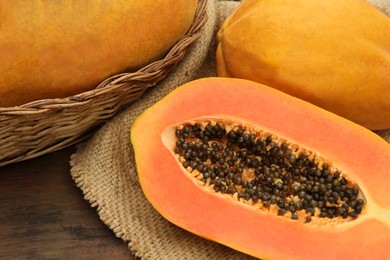 Tasty whole and cut papaya fruits on wooden table, closeup