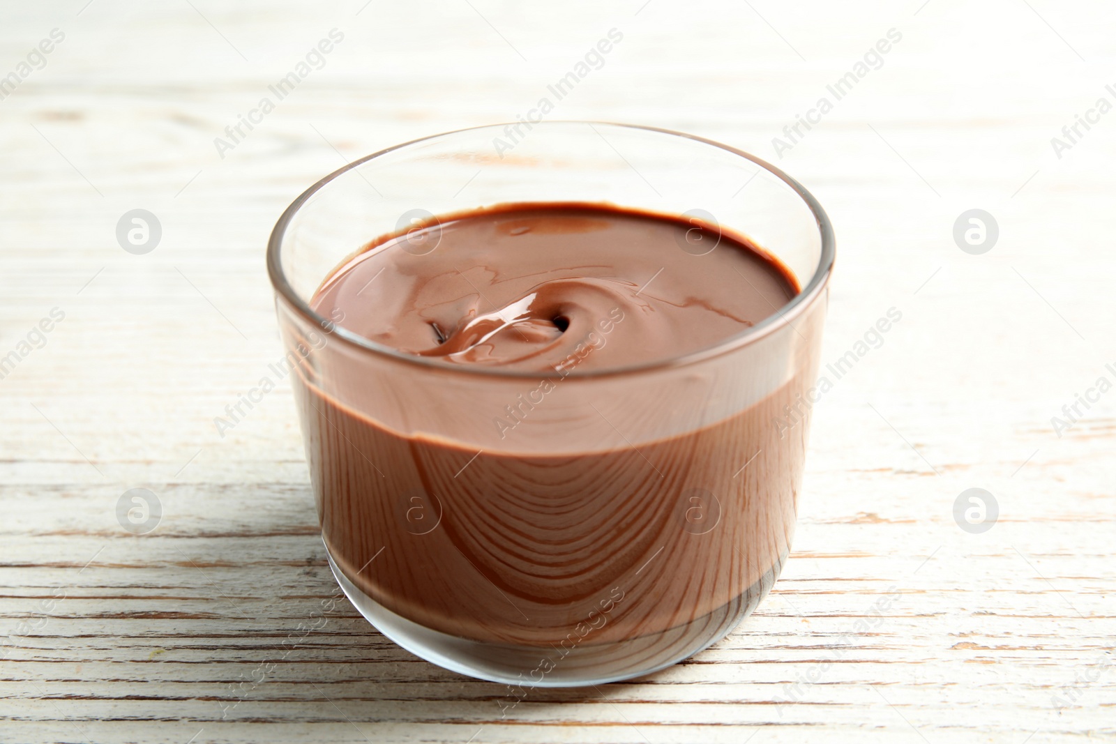 Photo of Glass with tasty chocolate cream on wooden table