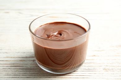 Glass with tasty chocolate cream on wooden table