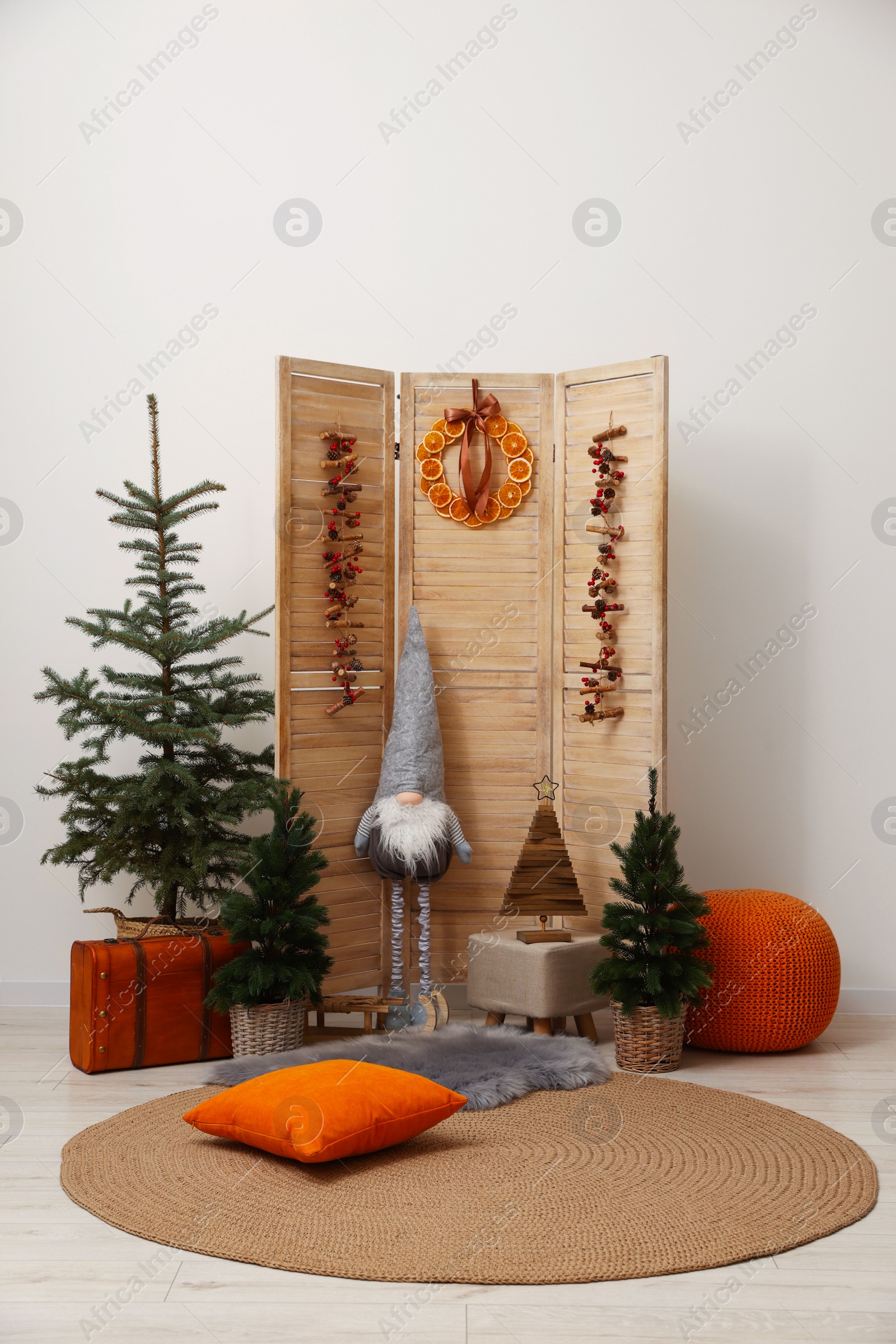 Photo of Beautiful Christmas themed photo zone with trees, dwarf and decor near white wall