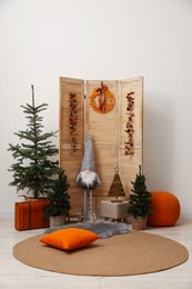Photo of Beautiful Christmas themed photo zone with trees, dwarf and decor near white wall