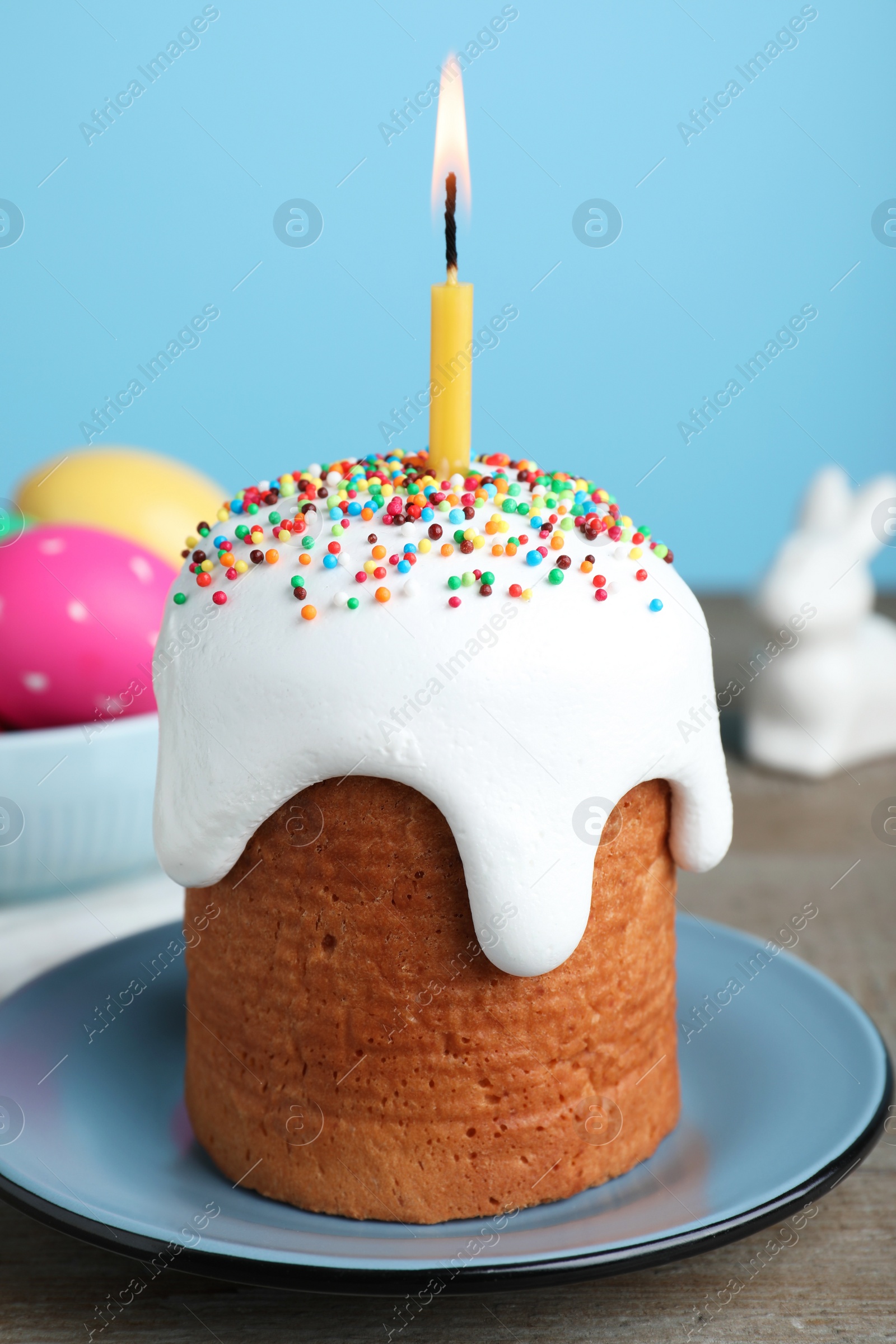 Photo of Easter cake with burning candle on wooden table