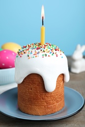 Photo of Easter cake with burning candle on wooden table